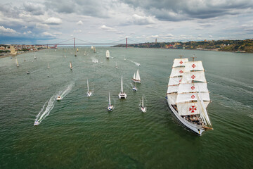 Aerial drone view of tall ships with sails sailing in Tagus river towards the Atlantic ocean in...