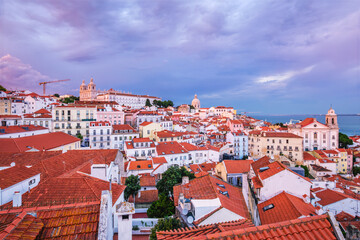 View of Lisbon famous view from Miradouro de Santa Luzia tourist viewpoint over Alfama old city district on sunset with dramatic overcast sky. Lisbon, Portugal.