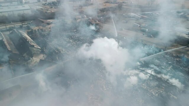 Drone above wide view of firemen fighting with fire near biulding 