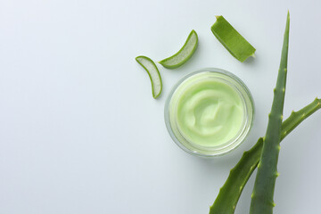 Jar of natural cream and cut aloe leaves on white background, flat lay. Space for text