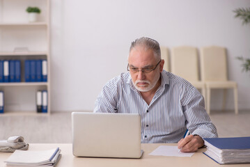 Old male employee working at workplace