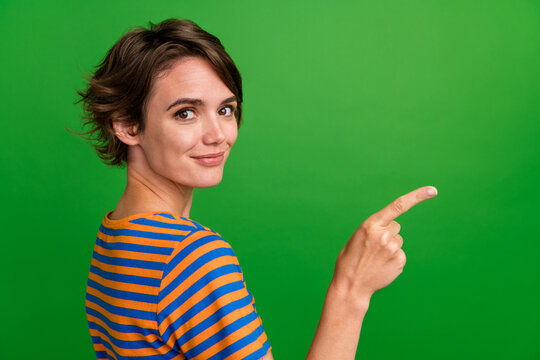 Profile photo of lovely positive girl indicate finger empty space proposition isolated on green color background