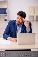 Young male employee sitting at workplace