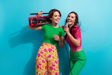 Photo of adorable pretty ladies wear colorful clothes singing boom box karaoke isolated blue color...