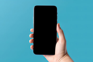 Hand holding smartphone with a black blank screen isolated on a blue background