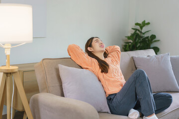 Obraz premium Women sitting on big sofa and holding hands behind head to napping and resting in lifestyle at home