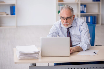 Fototapeta premium Old male employee working in the office