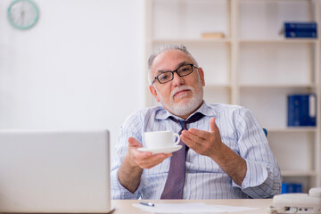 Old male employee drinking coffee during break