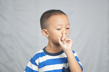 Asian boy sticks finger into nose