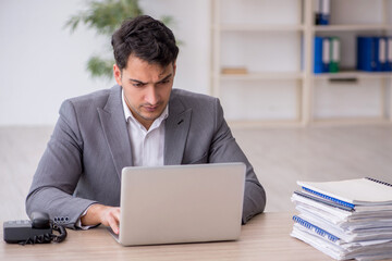 Young male employee and too much work in the office