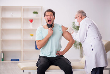 Young male patient visiting old male doctor in vaccination conce
