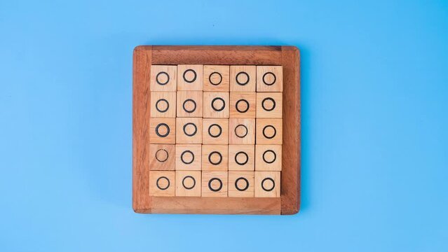 Stop motion animation of wooden game board tic-tac-toe. Turning of the letters X-O and middle one different from each other on blue background.