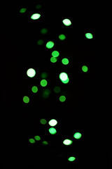 Green light, bokeh and glow on dark background isolated on a mockup space. Blur, black backdrop and defocused shine, sparkle or glitter at night for Christmas, holiday or party with magic color dots