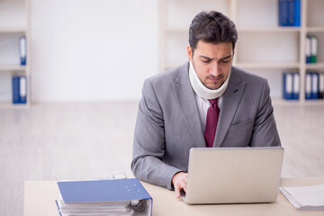 Young male employee after car accident sitting in the office