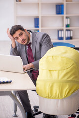 Young male employee looking after newborn at workplace