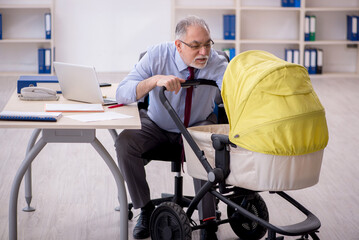 Old male employee looking after new born at workplace