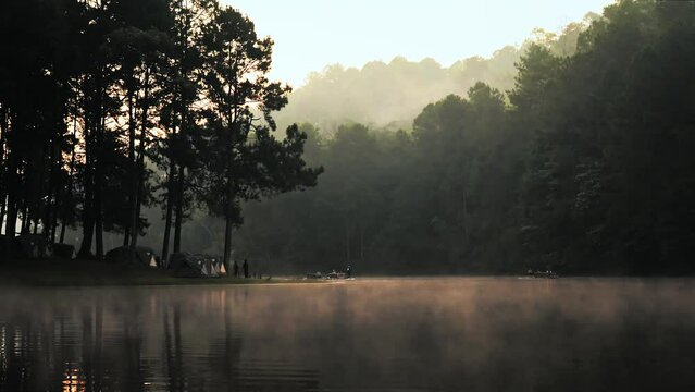 Timelapse of mist with sunlight on a lake with campsite. Sunrise at Pang Oung Lake in Thailand