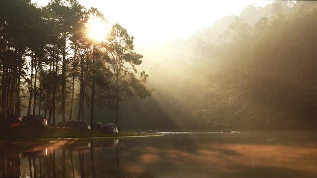 Rays of sunlight on a lake with campsite. Sunrise at Pang Oung Lake in Thailand