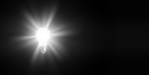 An illuminated or glowing lightbulb on a dark background represents new ideas, innovation,...