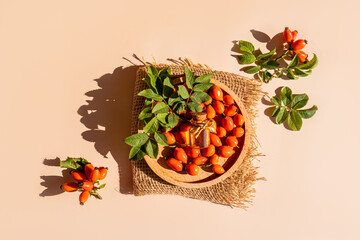 Top view of a glass bottle with a lid of organic rosehip seed oil on a round wooden tray with berries. natural care. An alternative to medicine.
