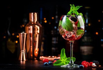 Mojito sangria cocktail drink with rum, sparkling wine, lime juice, raspberry, blueberry,...