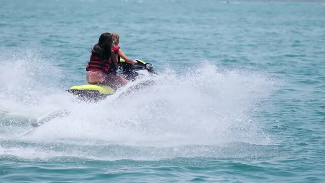 Two young women on a scooter floating in the sea bay of Dubai