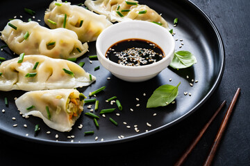 Gyoza - traditional japanese delicious dumplings filled with vegetables wrapped into thin dough served with soy sauce on wooden table
