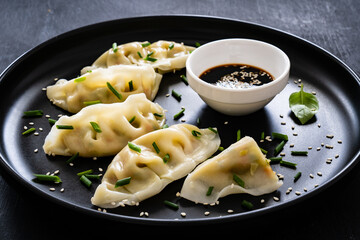 Gyoza - traditional japanese delicious dumplings filled with vegetables wrapped into thin dough served with soy sauce on wooden table
