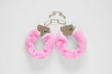 Pair of pink fur handcuffs on a white background