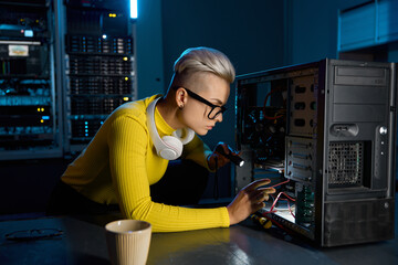 Young teenager hipster girl technician repairing computer part in datacenter