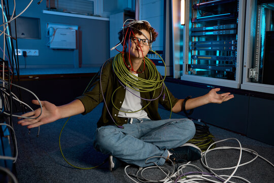 Confused IT networking engineer looking with disbelief on ethernet cables