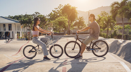 Young happy couple enjoy BMX riding at the skatepark