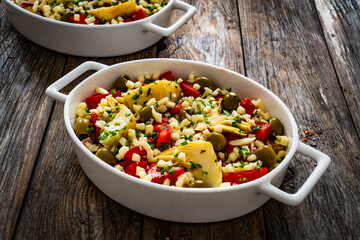 Bread casserole with mozzarella cheese, tomatoes, green olives, artichokes and scrambled eggs on wooden table
