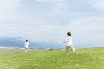 草原・公園でシャボン玉スティックで遊ぶ少年・兄弟・子供
