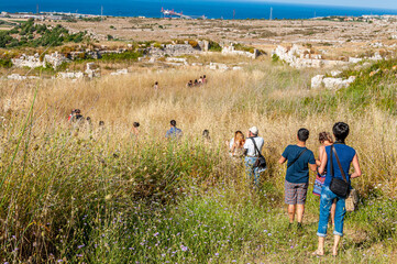 Gruppo di turisti in fila indiana in visita dei resti di antica città