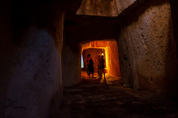 Gruppo di ragazze ascoltano la guida turistica in un antico tunnel sotterraneo a Siracusa
