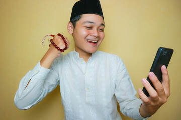 an Indonesian Muslim man of Asian descent wearing Muslim clothes and a black peci, celebrating Eid...