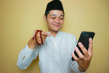 an Indonesian Muslim man of Asian descent wearing Muslim clothes and a black peci, celebrating Eid...