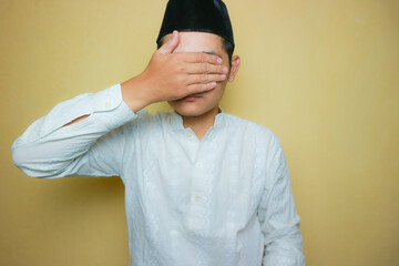 an Indonesian Muslim man of Asian descent wearing Muslim clothes and a black peci, celebrating Eid...