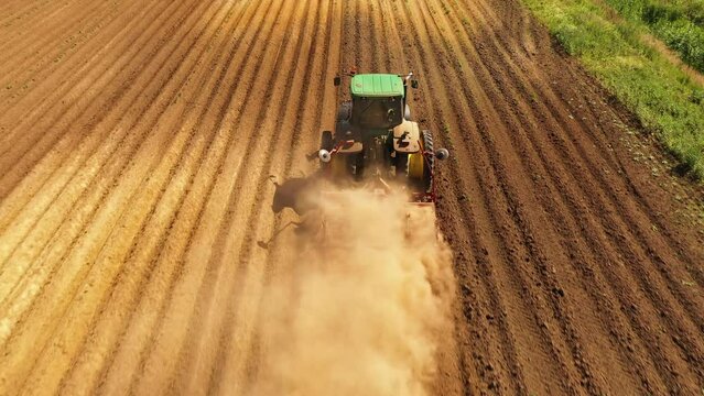 Tractor Hilling Potatoes with disc hiller in a potato field top view. Farmer in tractor preparing land with seedbed cultivator in farmlands