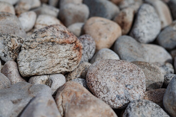 Abstract smooth round and sharp pebble nautical texture background. Stony shore of the sea or lake. Original stone texture. Close-up.
