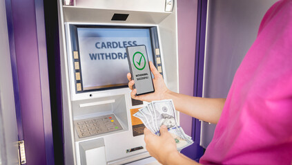 Young woman using the smart phone for cardless withdrawing the cash near the ATM