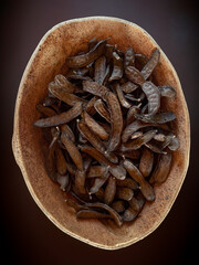 Dried carob pods close-up in a cork container.Isolated carob and carob background.