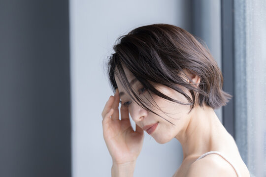 Beauty image of an Asian (Japanese) woman with an ennui expression, lying face down, pondering, melancholy and headache.