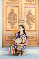 Girl in national traditional dress from Uzbekistan reading book
