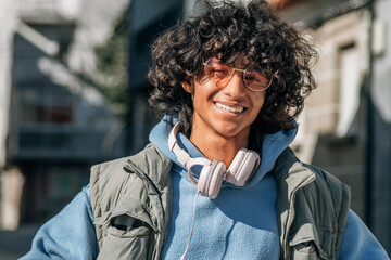 smiling young teenage man with headphones on the street