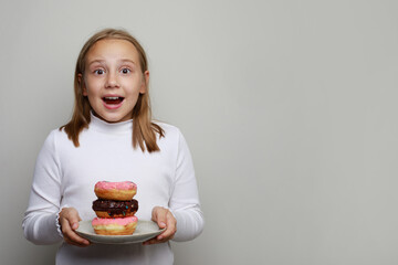 Cheerful happy surprised kid girl holding plate with colorful donut. Cute child having fun with doughnut  on white background. Sweet food, diet, happy birthday party, celebration and holiday concept