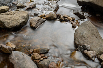 Tropical river flow on Semarang Central Java with green leaf and river stone. The photo is suitable to use for adventure content media, nature poster and forest background.