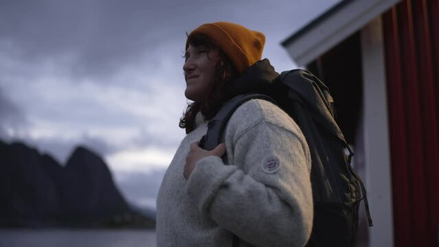 The dusky atmosphere of Lofoten, Norway sets the stage as a beautiful girl with a bag embarks on a solitary journey, her steps resonating with the enigmatic mood.