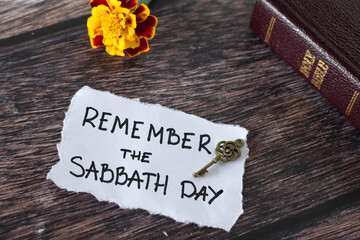 Remember the Sabbath Day, handwritten quote with ancient key, holy bible book, and flower on wooden...